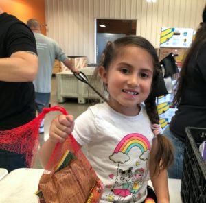 Child holds student snack bag at Community Food Bank of San Benito County