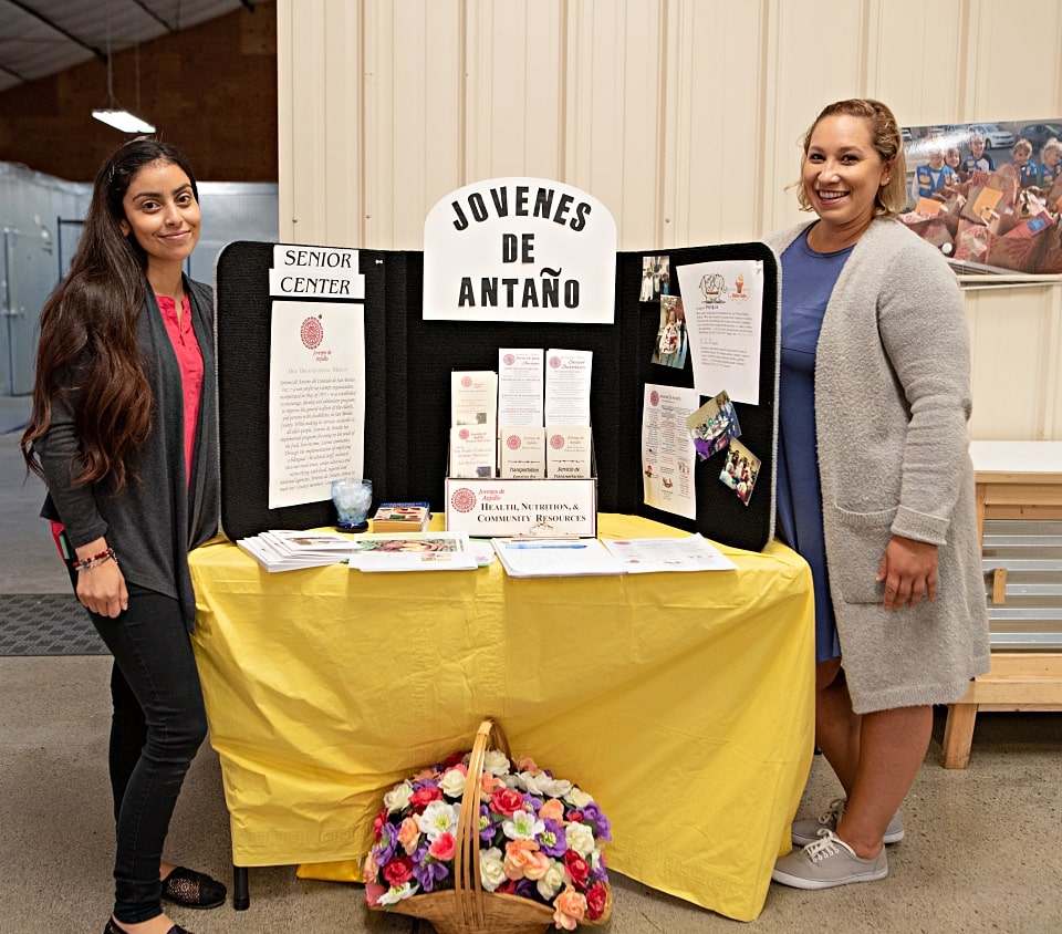 Representatives from Jovenes de Antano standing at display table during wellnes fair at Food Bank of San Benito County