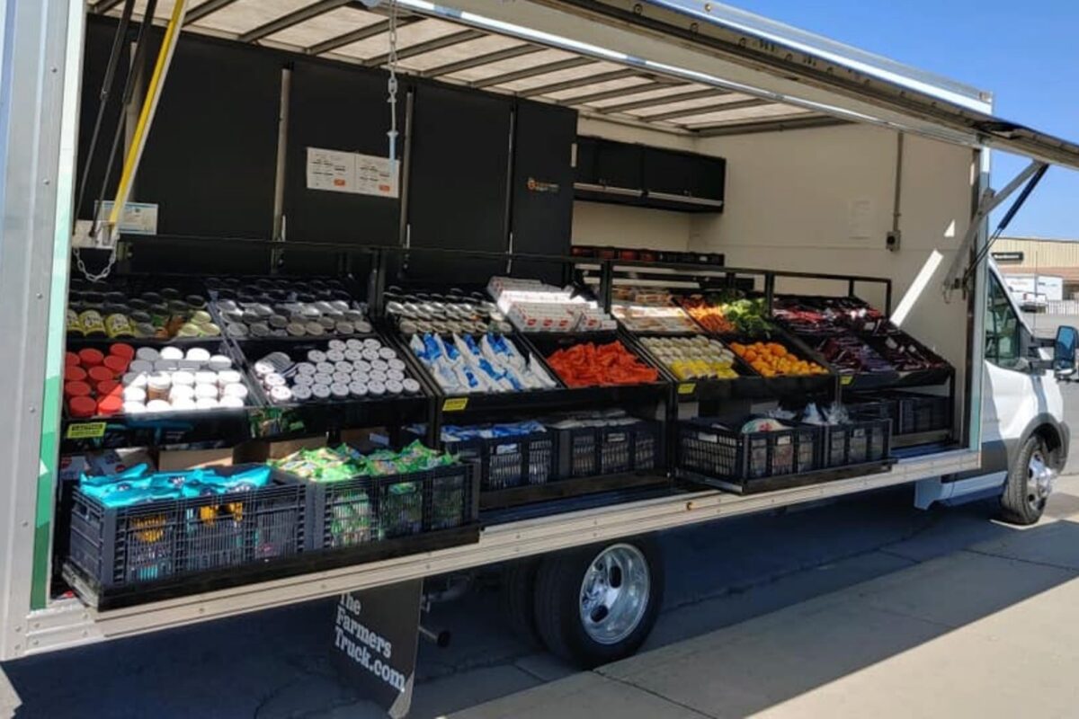 Community Food Bank of San Benito County's mobile food pantry truck parked on the street with its pantry door open to display and distribute food.